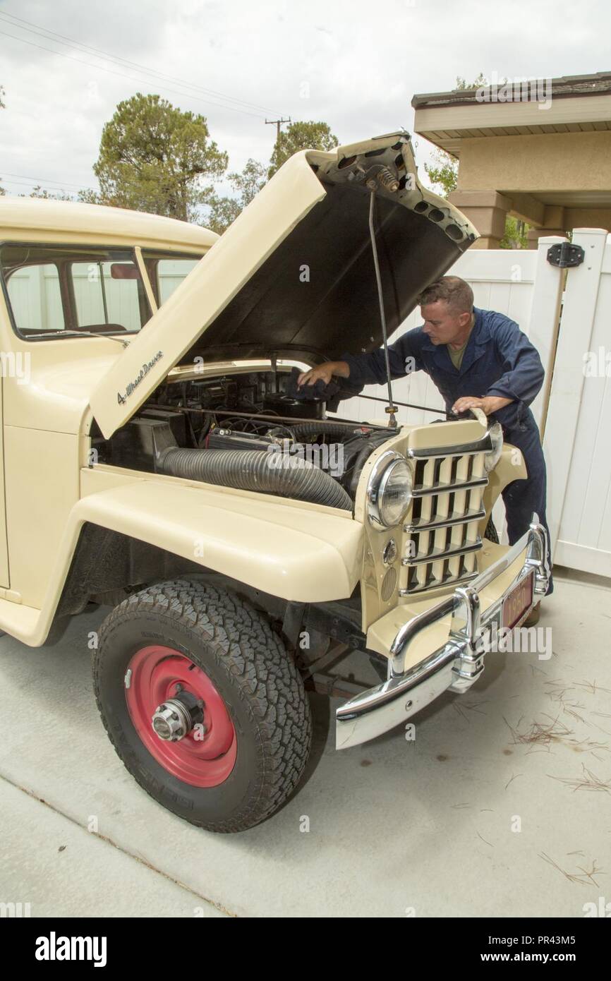 Lieutenant Colonel Timothy Silkowski, director of Fleet Support Division, adjusts the intake manifold on the carburator of his 1950 Jeep Willys Station Wagon, aboard Marine Corps Logistics Base Barstow, Calif., July 25. He found the vehicle abandoned and burried up to the wheel wells in sand, and has worked diligently to restore it in his free time. Stock Photo