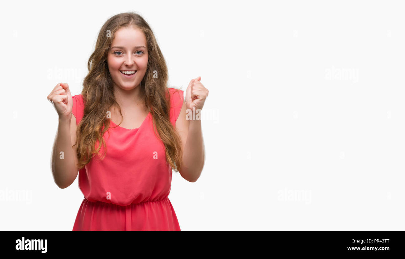 Young blonde woman wearing pink dress screaming proud and celebrating victory and success very excited, cheering emotion Stock Photo