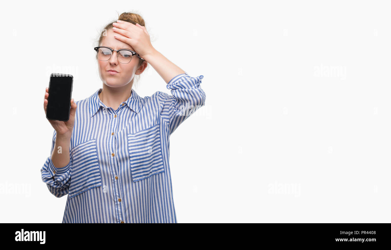 Young blonde woman using smartphone stressed with hand on head, shocked with shame and surprise face, angry and frustrated. Fear and upset for mistake Stock Photo