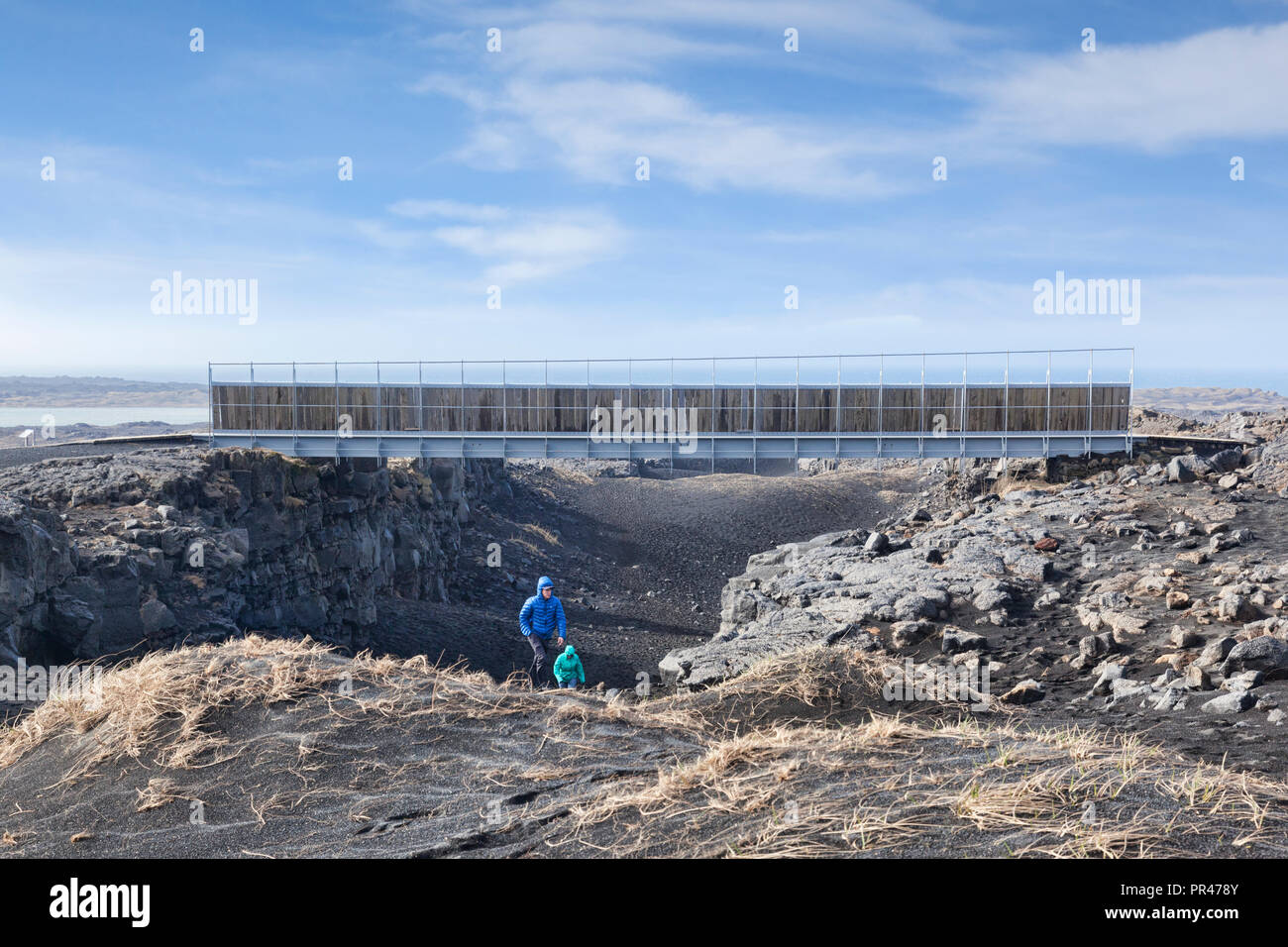 18 April 2018: Sandvik, Iceland - A couple emerging from the gorge at the symbolic Bridge Between Continents in the Reykjanes Peninsula, Iceland, cros Stock Photo