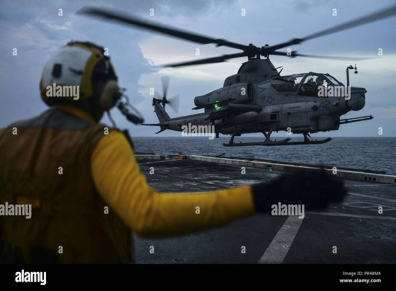INDIAN OCEAN (Dec. 30, 2017) Aviation Boatswain Mate Handling Airman Ryan Sharland, from Newport Beach, Calif., directs a AH-1Z Viper attack helicopter, attached to Marine Medium Tiltrotor Squadron (VMM) 161 (reinforced), on the flight deck of the amphibious transport dock ship USS San Diego (LPD 22). San Diego, part of the America Amphibious Ready Group, with embarked 15th MEU, is operating in the Indo-Asia-Pacific region to strengthen partnerships and serve as a ready-response force for any type of contingency. Stock Photo