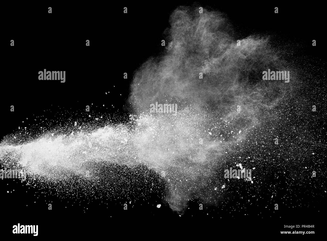 Bizarre forms of white powder explosion cloud against black background.White dust particles splash. Stock Photo