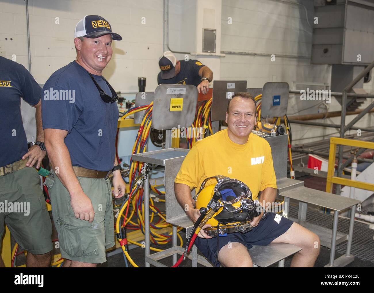 PANAMA CITY, Florida - Rear Adm. Tom Anderson (right) holds a KM-37 dive helmet as he prepares for a dive in the NEDU Navy Experimental Diving Unit. Anderson is pictured with Navy Diver Chief Andy Swartwood (left) who served as his Diver Tender during a diving operation in the test pool Sept. 5, 2018. U.S. Navy Stock Photo