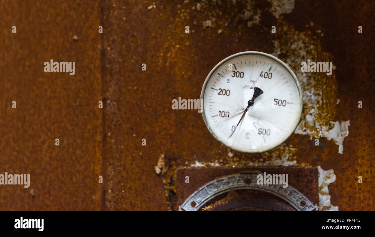 The old broken temperature gauge with rusty iron background Stock Photo