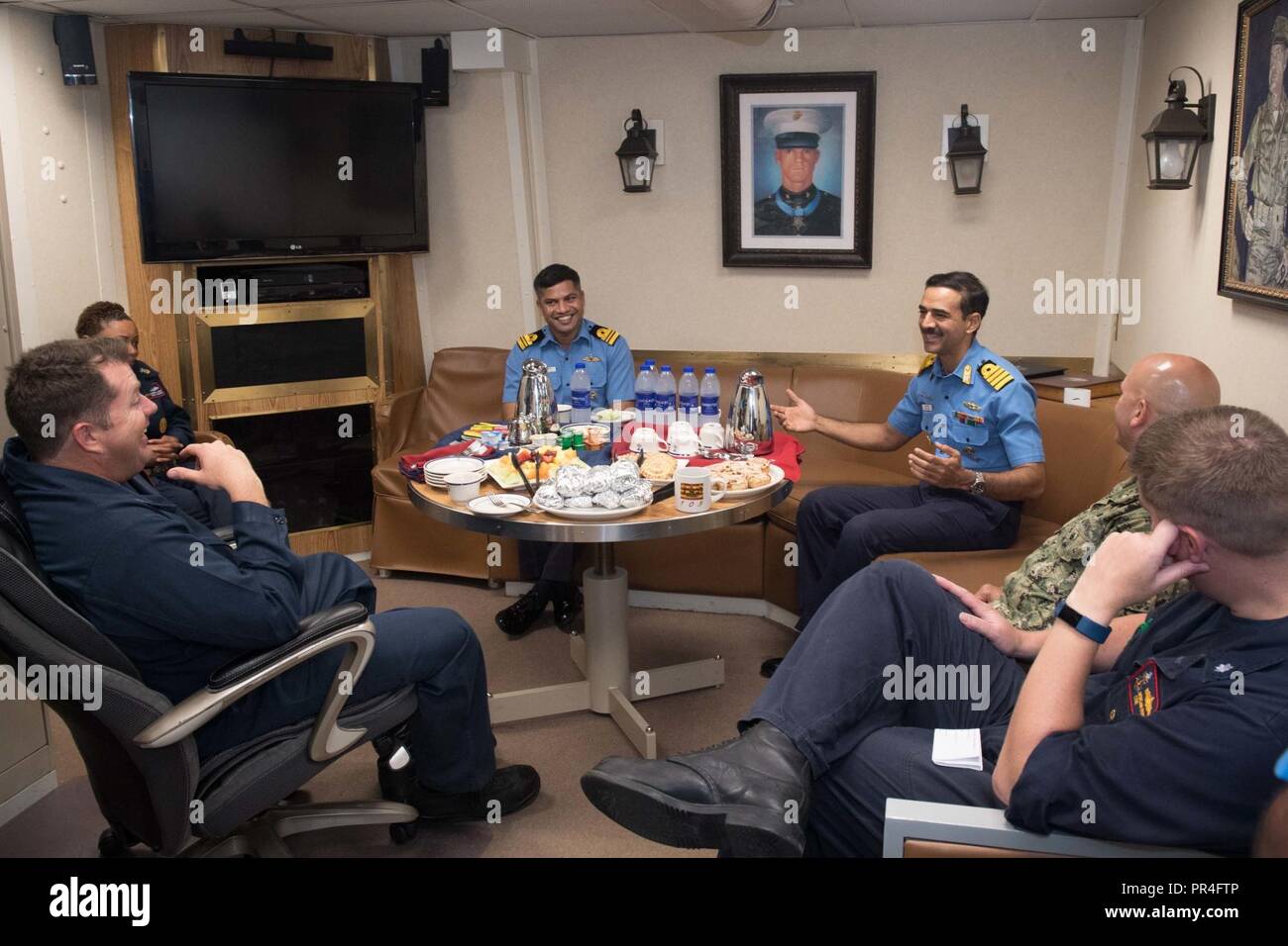 U.S. 5TH FLEET AREA OF OPERATIONS (Sept. 12, 2018) U.S. Navy Sailors and Indian Navy sailors meet together in the captain’s cabin aboard the guided-missile destroyer USS Jason Dunham (DDG 109) during a Combined Maritime Forces coordinated officer exchange and shipboard visit to discuss naval interoperability. Dunham is deployed to the U.S. 5th Fleet area of operations in support of naval operations to ensure maritime stability and security in the Central Region, connecting the Mediterranean and the Pacific through the western Indian Ocean and three strategic choke points. Stock Photo