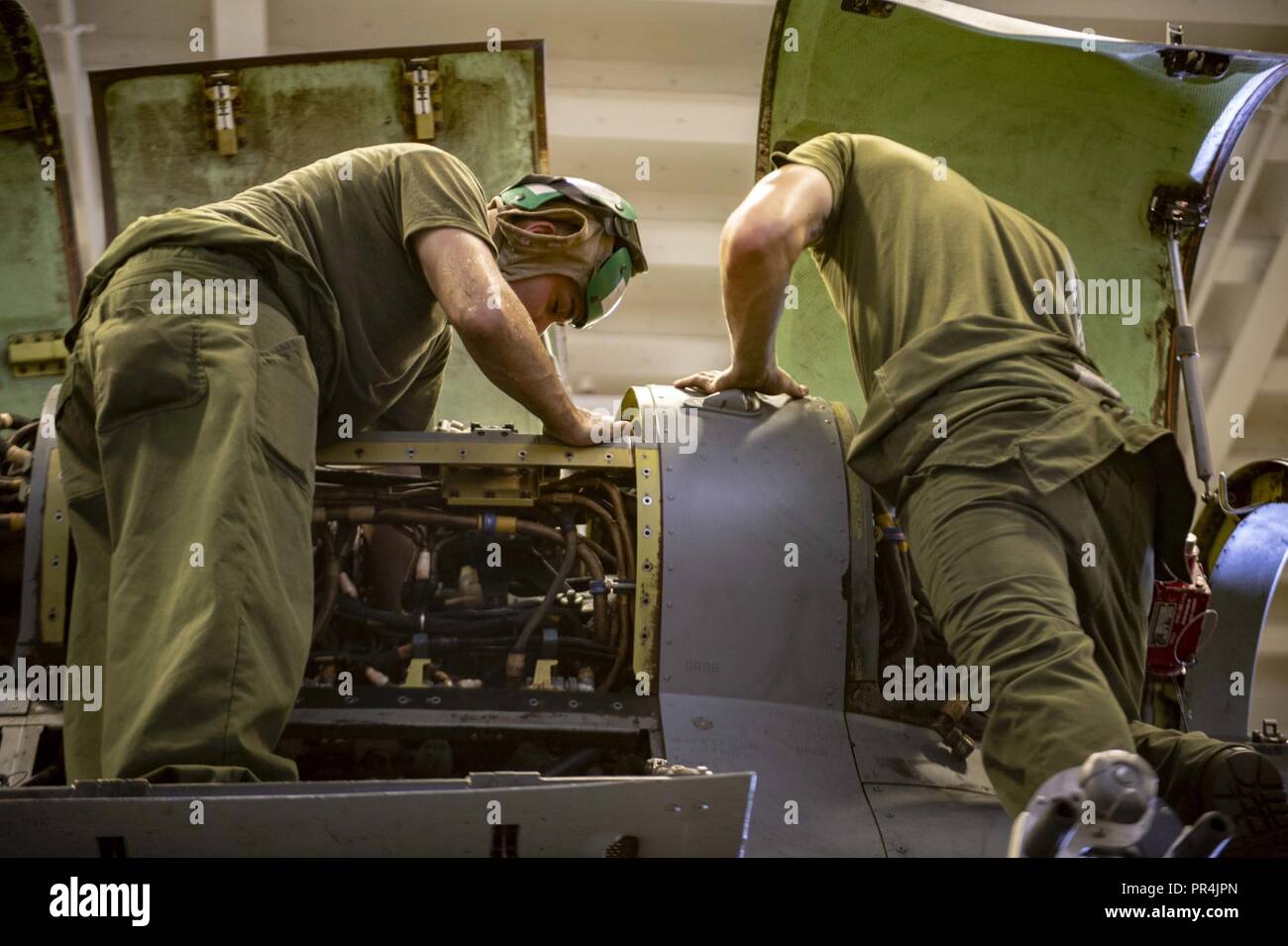 OF ADEN (Sept. 13 2018) – Marine Corps Staff Sgt. Javier Castillo and Marine Corps Lance Cpl. Brandon Barnett perform maintenance on an MV-22 Osprey tiltrotor aircraft, attached to the “Sea Elks” of Marine Medium Tiltrotor Squadron (VMM) 166 (REIN), aboard Wasp-class amphibious assault ship USS Essex (LHD 2) during a regularly scheduled deployment of Essex Amphibious Ready Group (ARG) and 13th Marine Expeditionary Unit (MEU). The Essex ARG/13th MEU is a lethal, flexible, and persistent Navy-Marine Corps team deployed to the U.S. 5th Fleet area of operations in support of naval operations to en Stock Photo