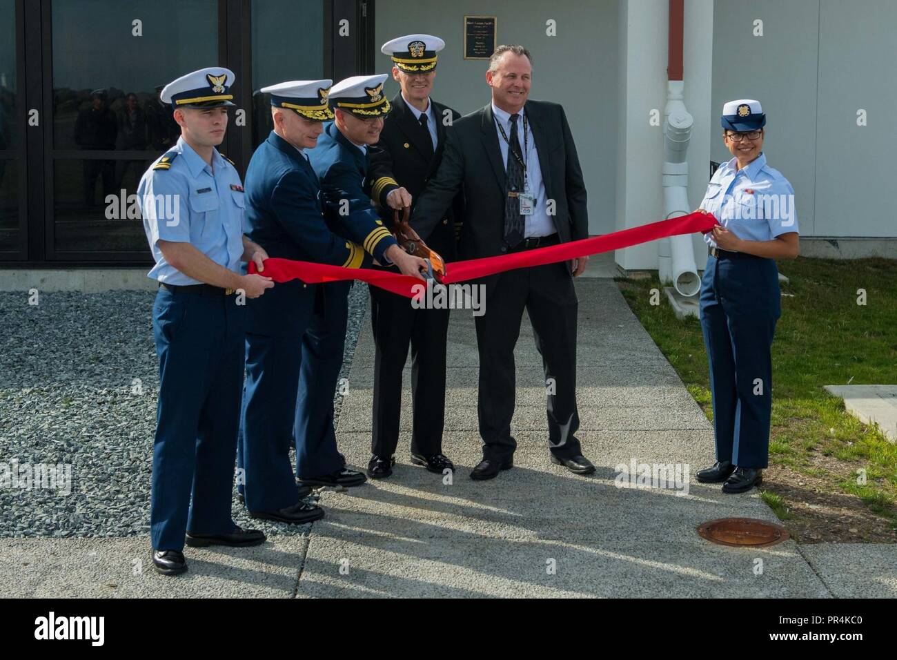 PORT ANGELES, Wash. (Sep. 14, 2018) Rear Adm. David Throop, commander, Coast Guard Thirteenth District, Coast Guard Cmdr. Thomas Evans, commanding officer, Maritime Force Protection Unit-Bangor, Capt. Chad Brooks, commanding officer, Naval Facilities Engineering Command Northwest, and Theo Cragg, the operations management department head for Strategic Weapons Facility Pacific, (left to right), cut the ribbon during a ceremony for the official opening of the Transit Protection System facilities at the U.S. Coast Guard Air Station Sector Field Office, Port Angeles. The project consisted of const Stock Photo