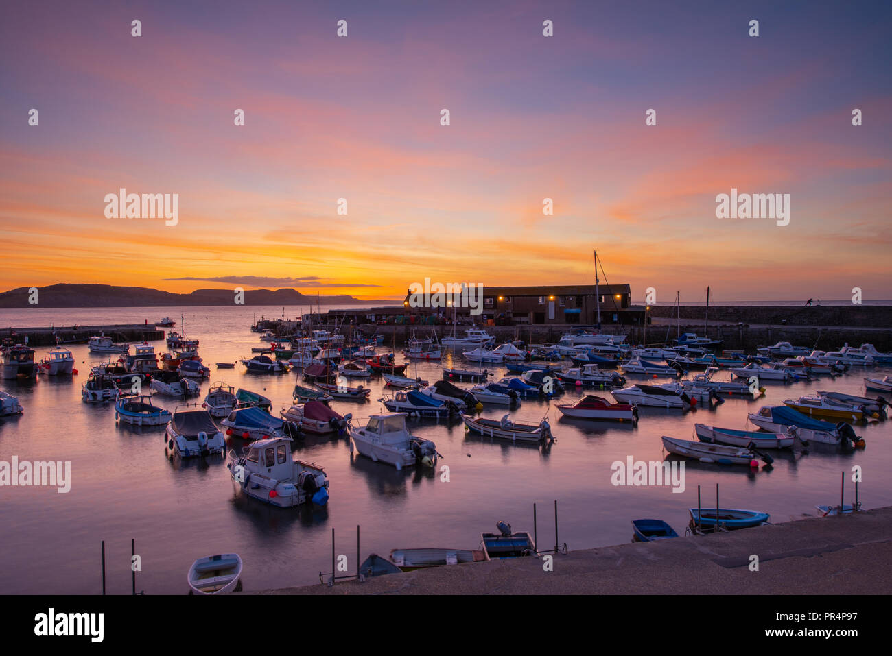 Lyme Regis, Dorset, UK. 29th September 2018.  UK Weather:  The skies over the Cobb Harbour glow with vibrant colour at the start of a sunny day at Lyme Regis.  Credit: Celia McMahon/Alamy Live News Stock Photo