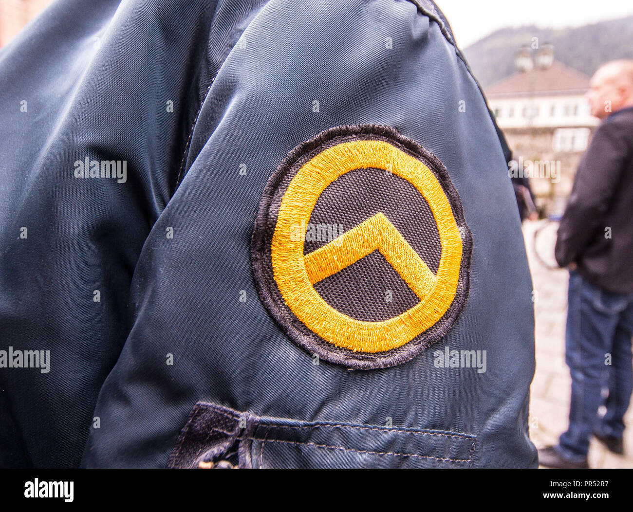 Garmisch Partenkirchen, Bavaria, Germany. 29th Sep, 2018. Logo of the Identitaere Bewegung worn by a person that appeared to be working in a security capacity at the Compact Konferenz in Garmisch Partenkirchen. Adding themselves to the 'who's who'' list of of several hundred right-extremists from Germany, Austria, Switzerland, and other countries, Tommy Robinson, founder of the British EDL, Lutz Bachmann, grounder of Germany's Pegida, and Martin Sellner of the Identitaere Bewegung were guests as the Compact Konferenz held in the international tourist town of Garmisch Partenkirchen Stock Photo