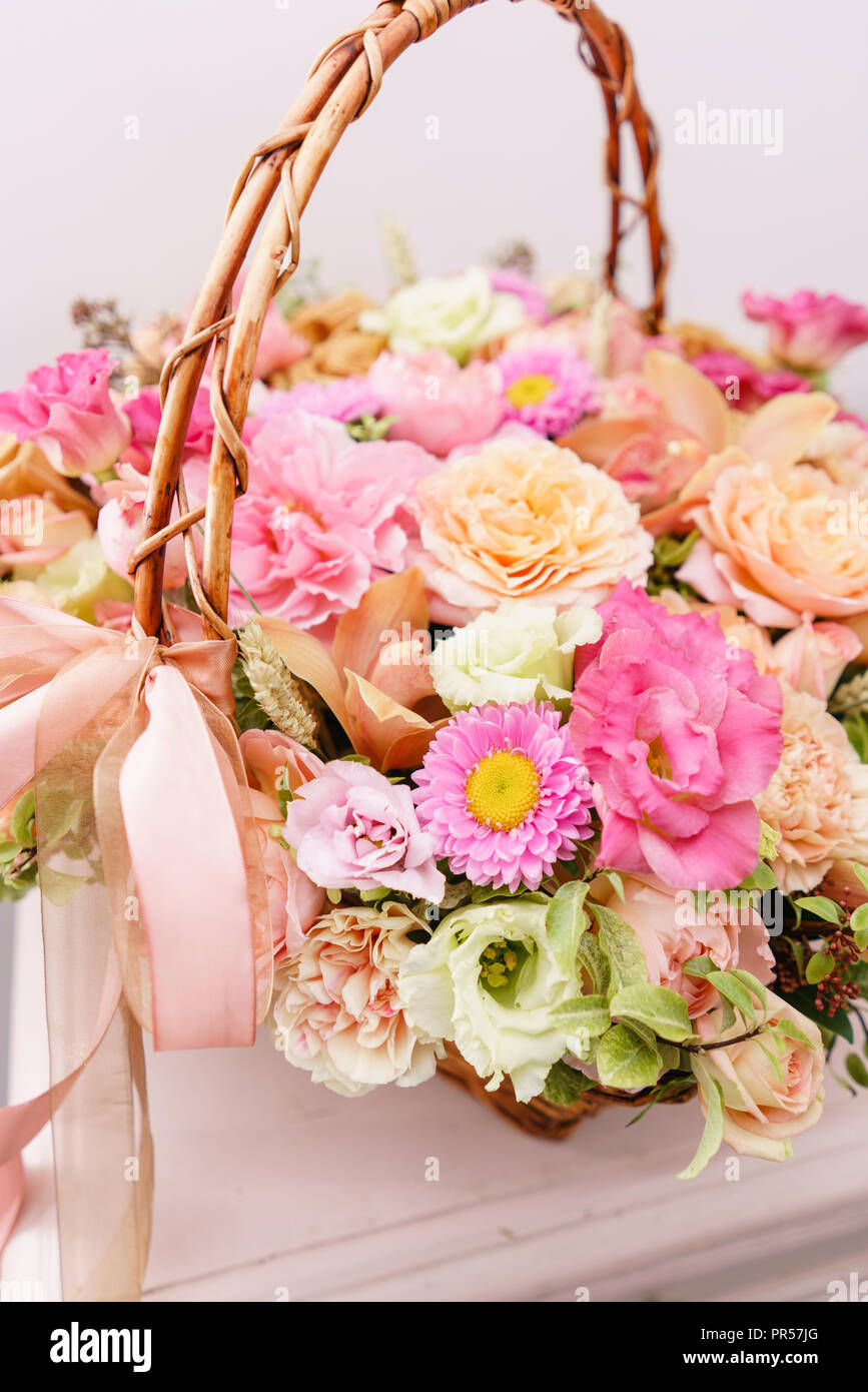 flowers arrangement with various of colors in wicker basket on pink