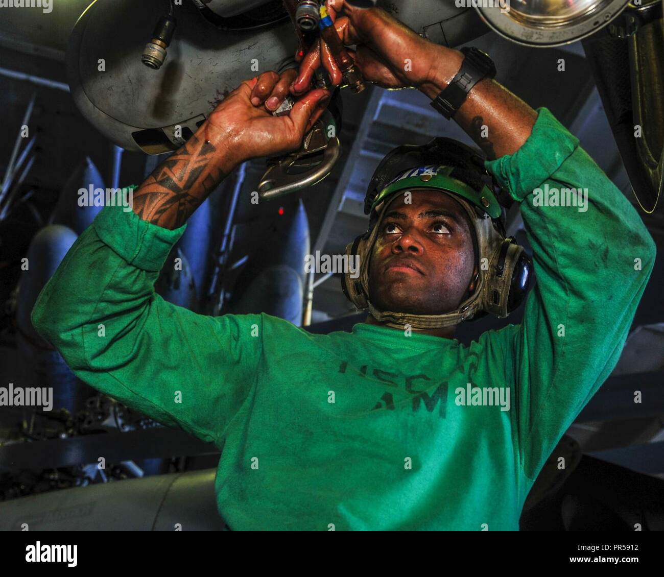PHILIPPINE SEA (Sept. 15, 2018) Aviation Mechanic Airman Joel-Marc Lobban, from Kingsland, Jamaica, performs maintenance on an MH-60S Sea Hawk helicopter assigned to Helicopter Sea Combat Squadron (HSC) 12 in the hangar bay of Navy’s forward-deployed aircraft carrier USS Ronald Reagan (CVN 76) in preparation for the Valiant Shield 2018 exercise. Valiant Shield is a U.S. only, biennial field training exercise (FTX) with a focus on integration of joint training in a blue-water environment among U.S. forces. This training enables real-world proficiency in sustaining joint forces through detecting Stock Photo