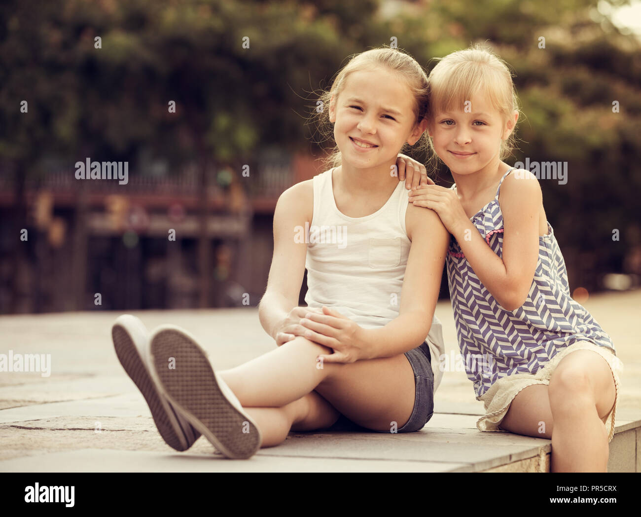 Two smiling little girls embracing each other in summer park Stock ...