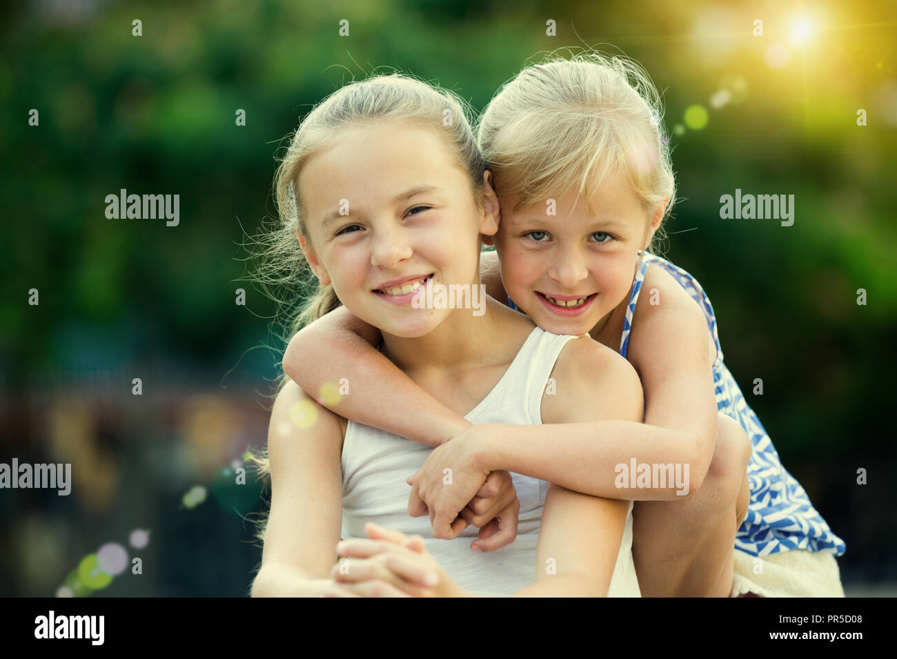 Two smiling little girls embracing each other in summer park Stock ...