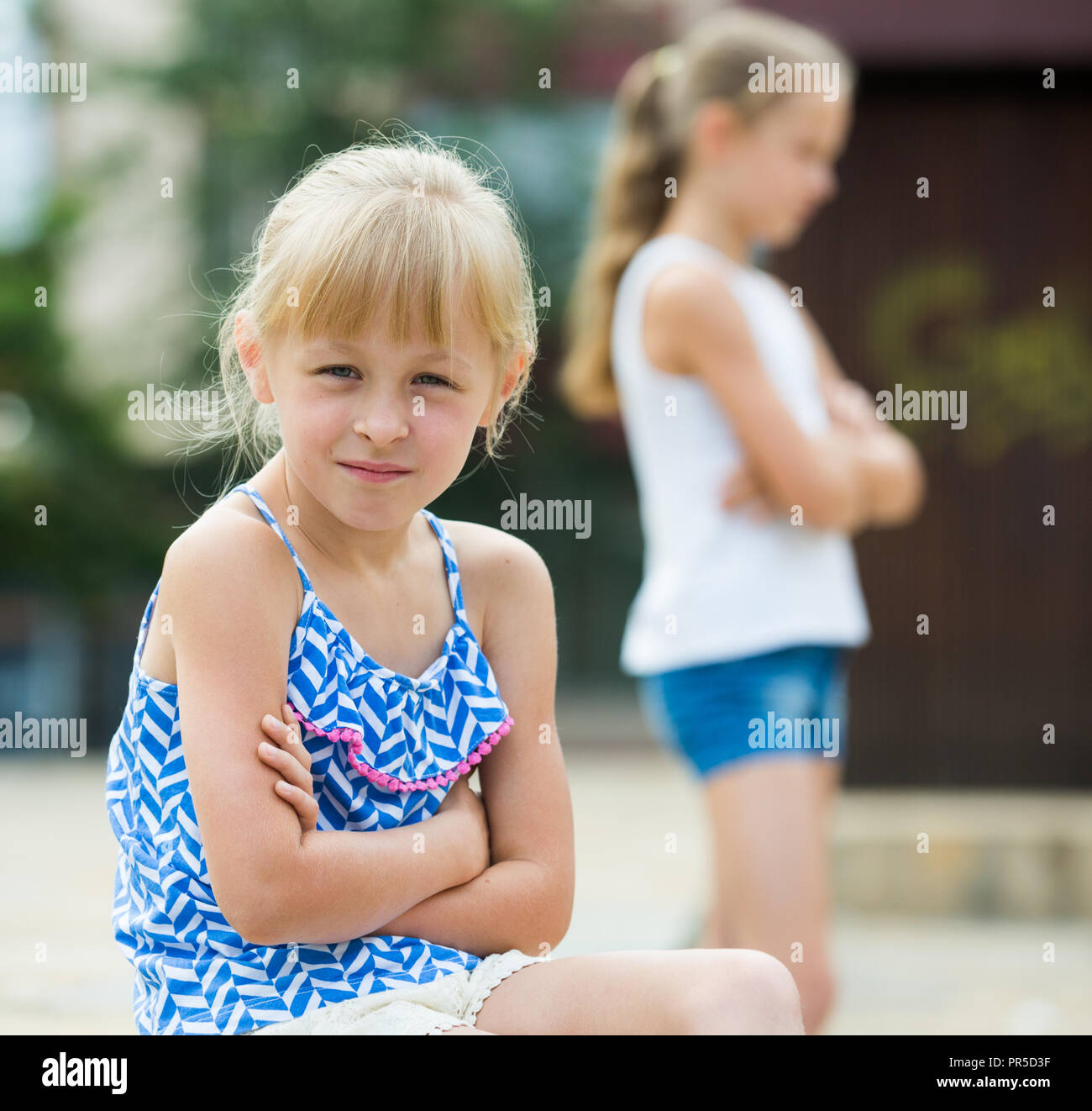 Two offended little girls not talking to each other after quarrel outdoors Stock Photo