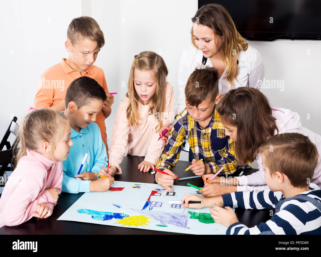 Portrait glad team of elementary age children and teacher drawing on ...