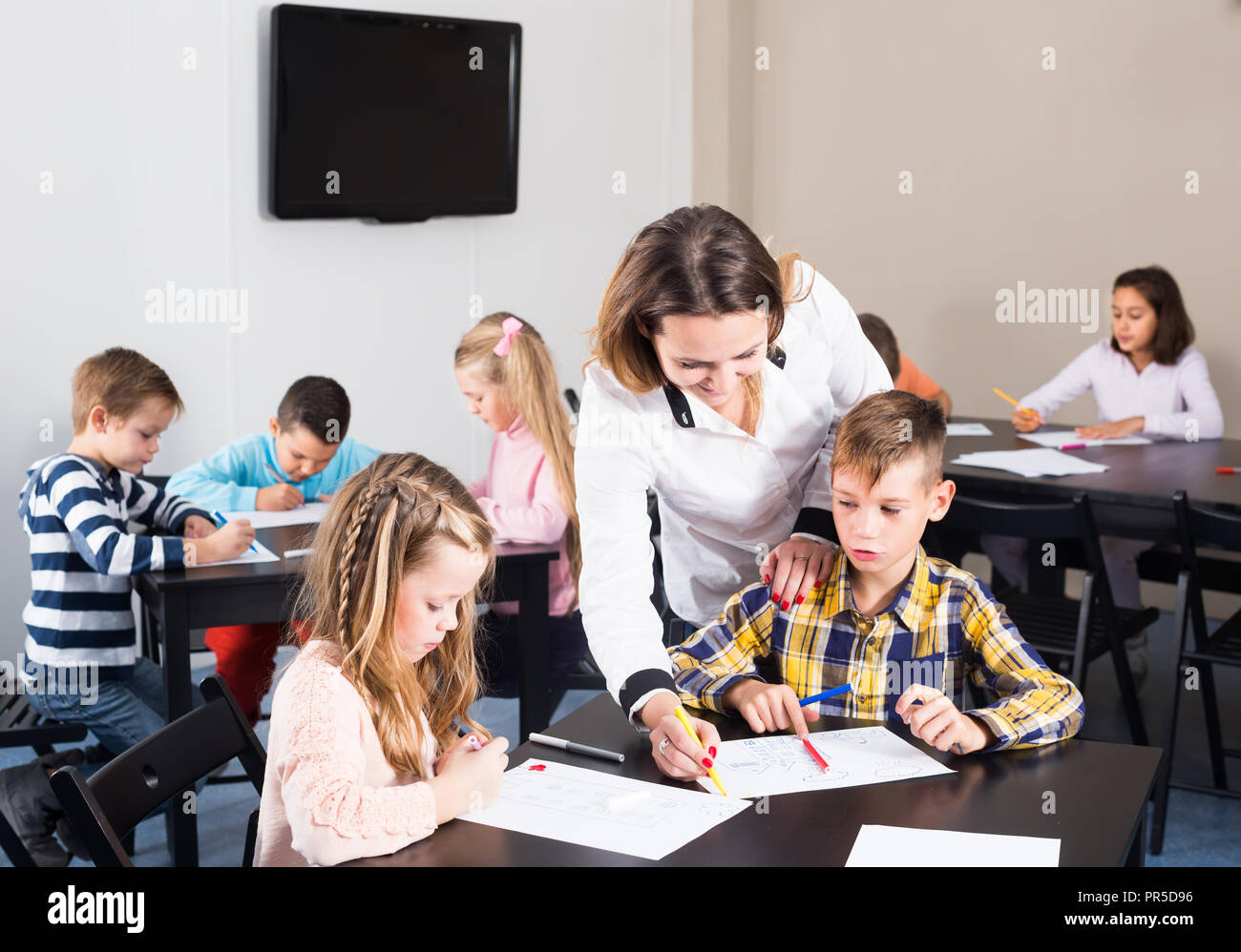 Little children with smiling teacher drawing in classroom on the lesson ...
