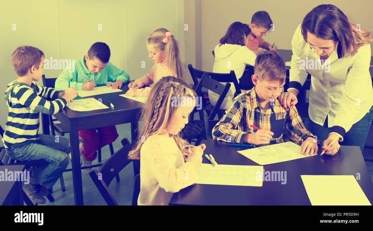 Little friendly children with teacher drawing in classroom on the ...