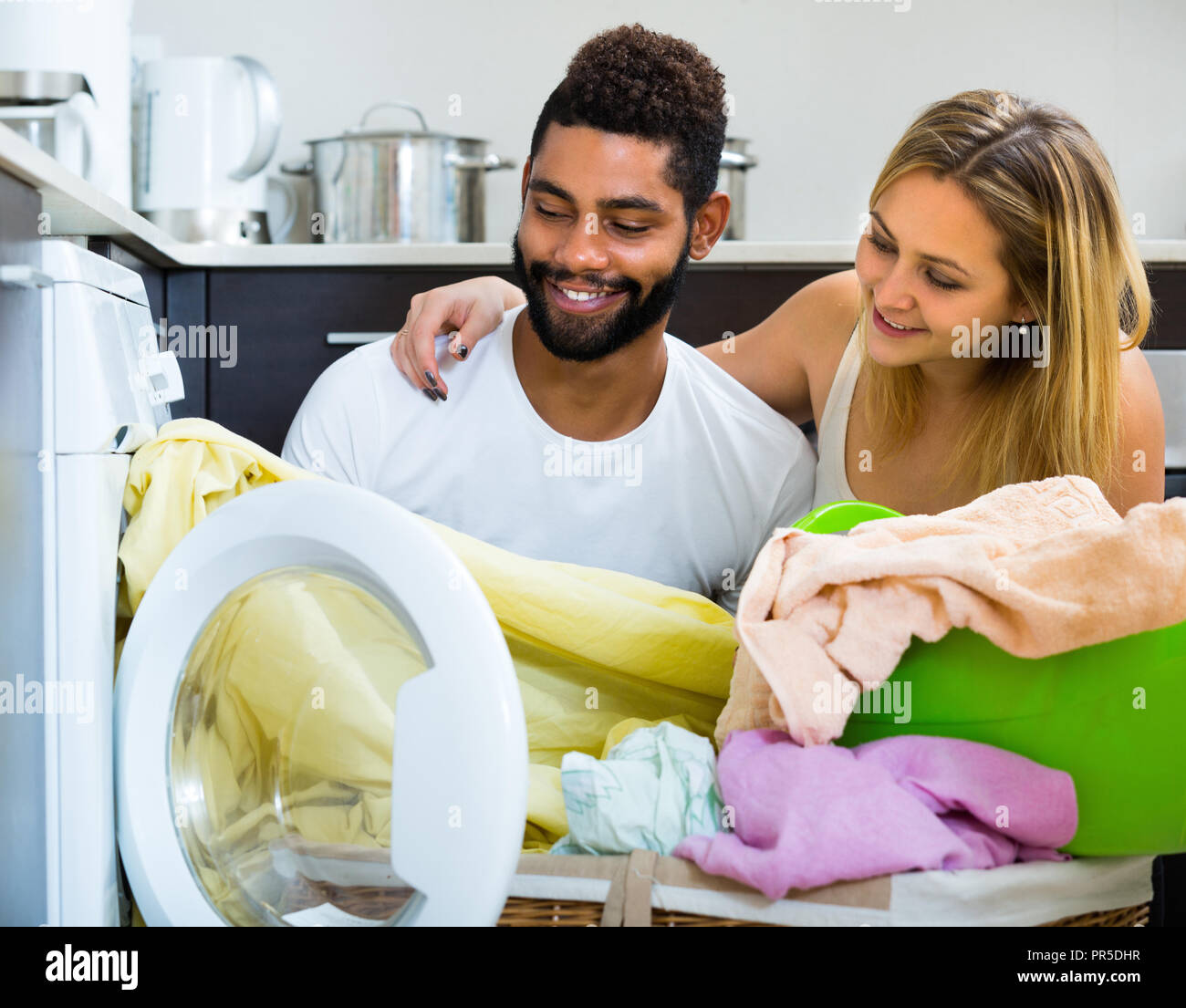 Happy smiling young mixed spouses doing regular laundry at home Stock Photo