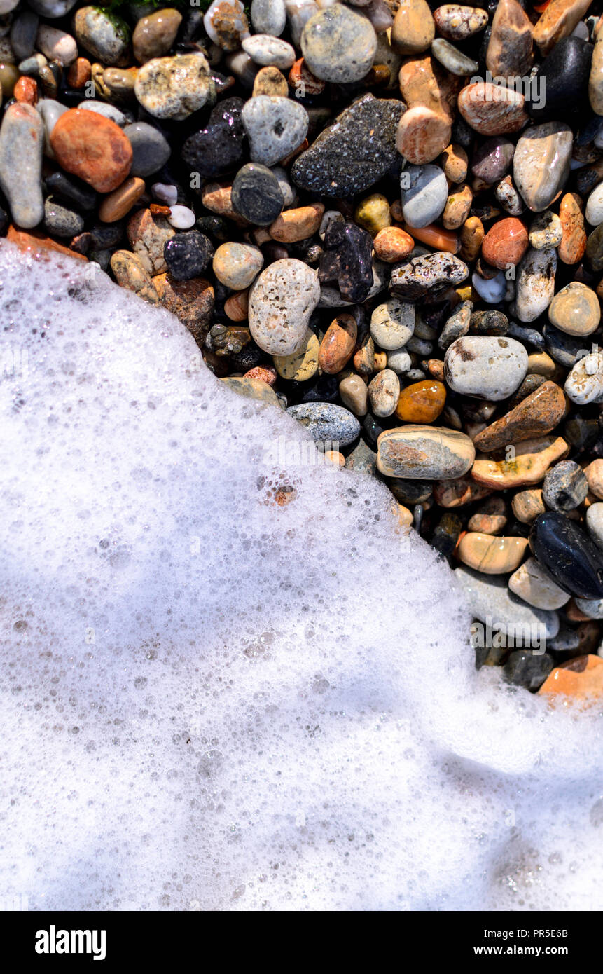 Pebbles on the beach with waves foam Stock Photo