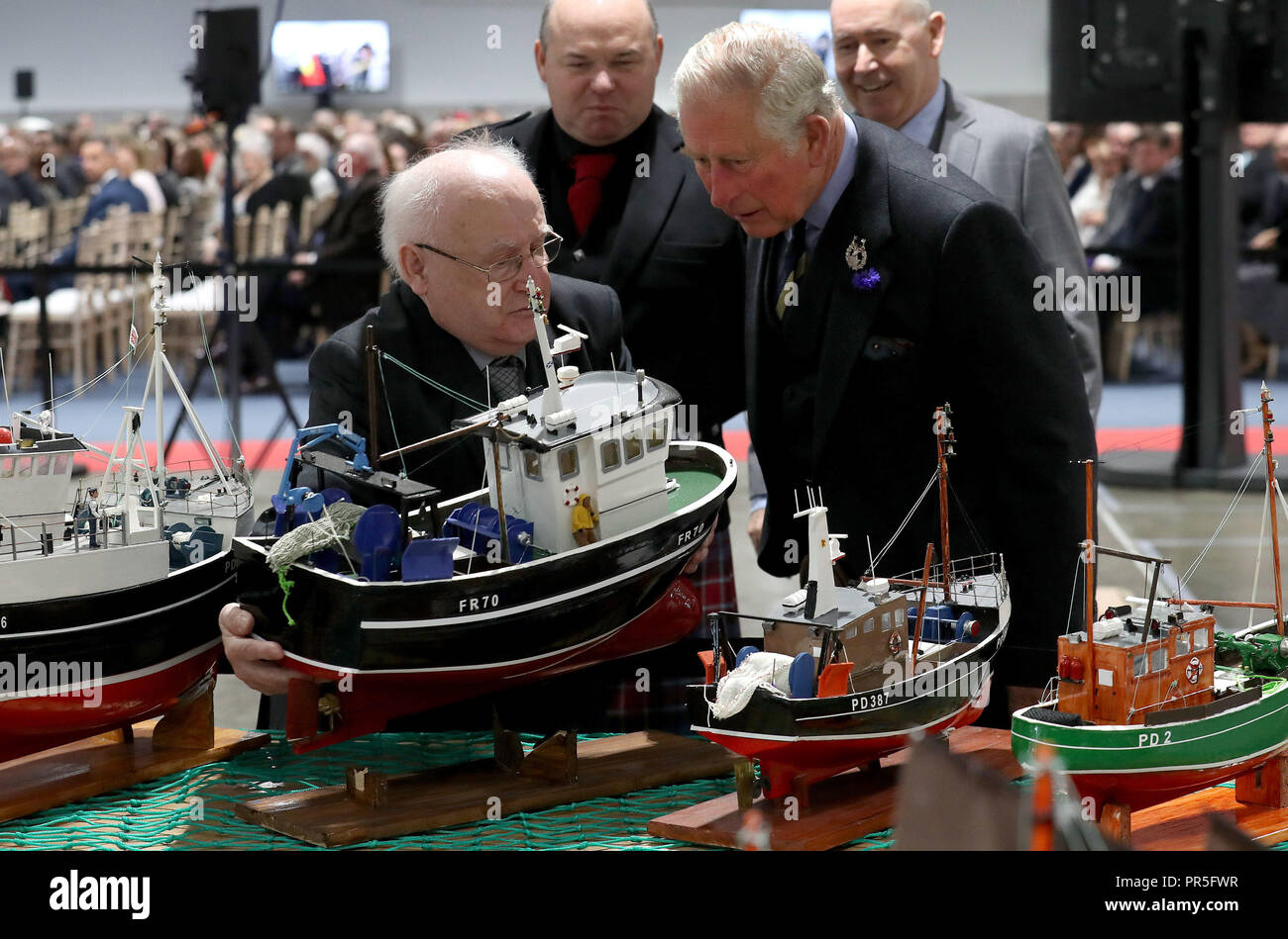 The Prince of Wales known as the Duke of Rothesay whilst in Scotland, is shown a model fishing boat by its maker John Coull during a visit to Peterhead fish market for the opening of the new North Bay market building. Stock Photo