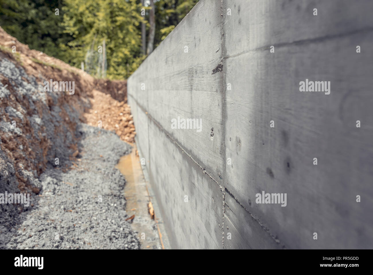 Dug out shaft next to a newly build concrete wall outside in a home
