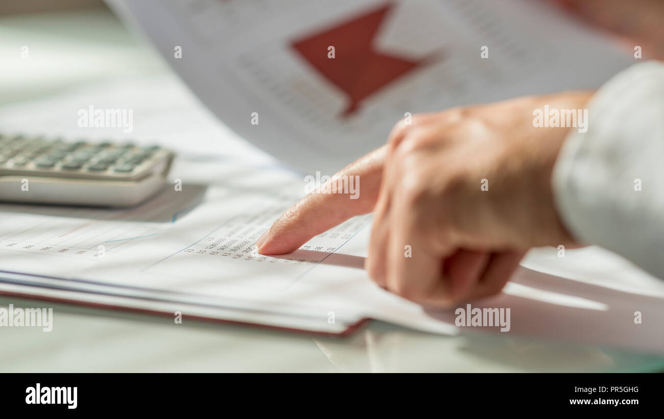 Closeup of male hand pointing to figures written on a document or report in form of statistical data. Conceptual of economy, finance and accounting. Stock Photo