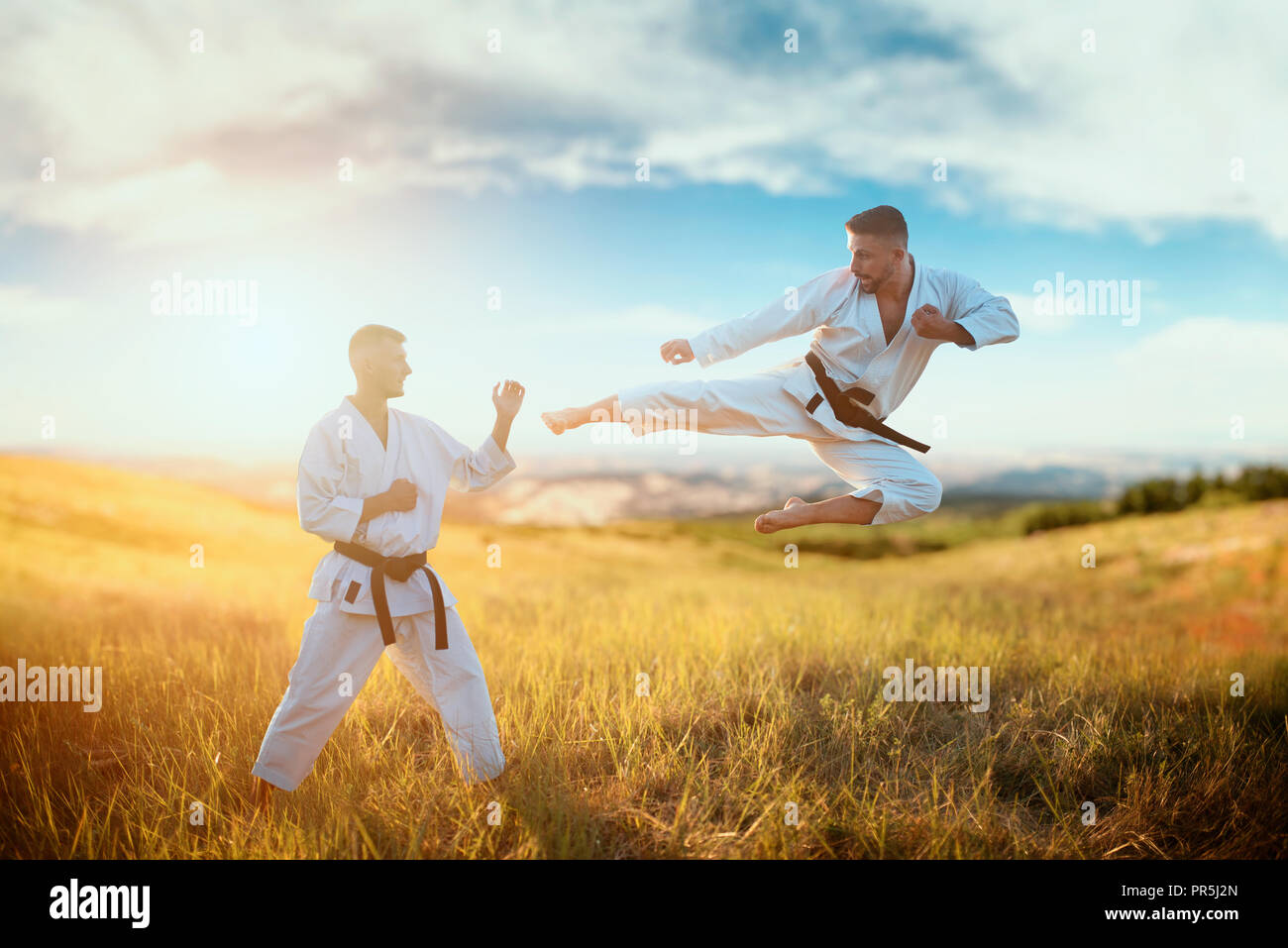 Karate fighters, kick in flight on training fight in summer field
