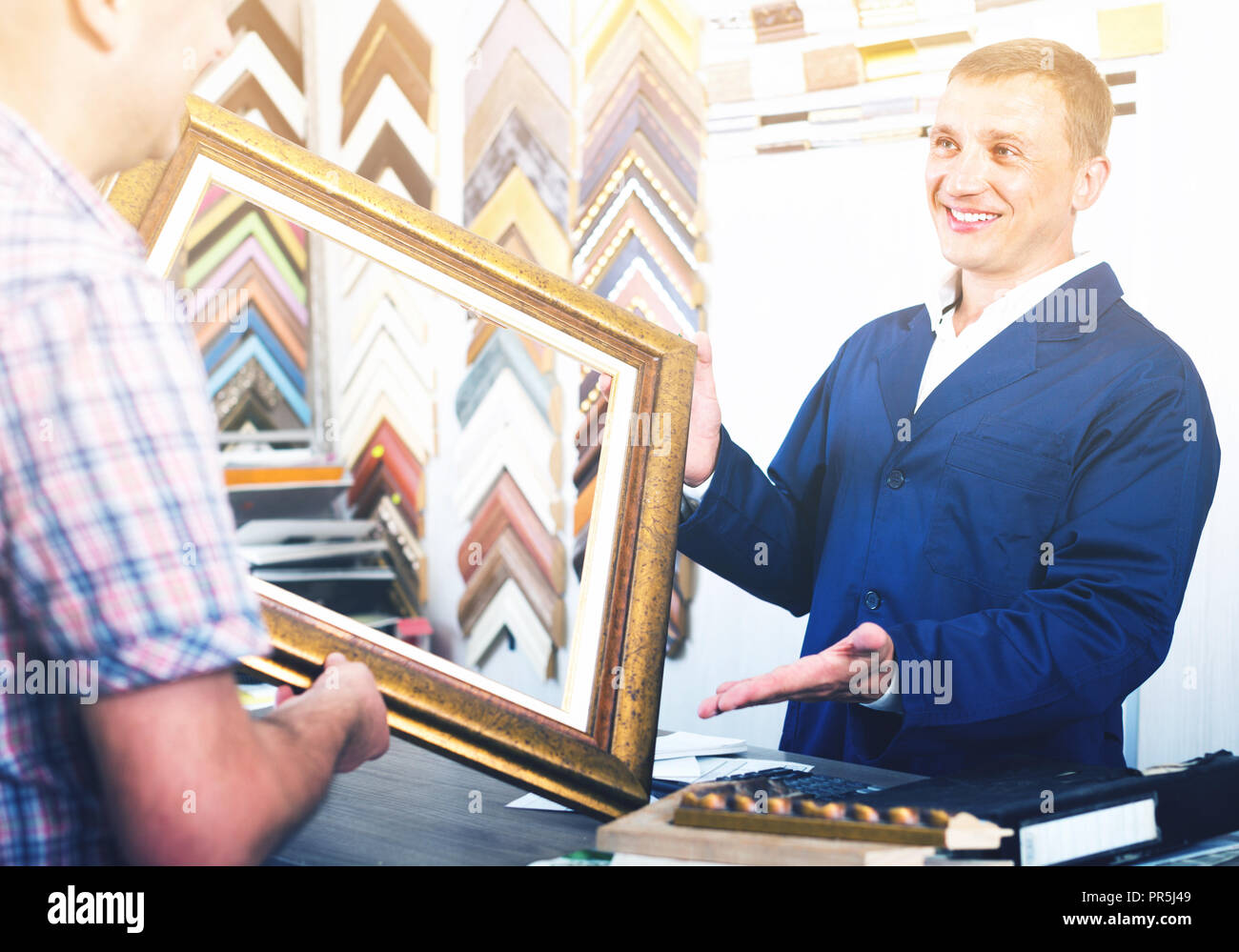 man seller talking to customer in picture framing studio Stock Photo