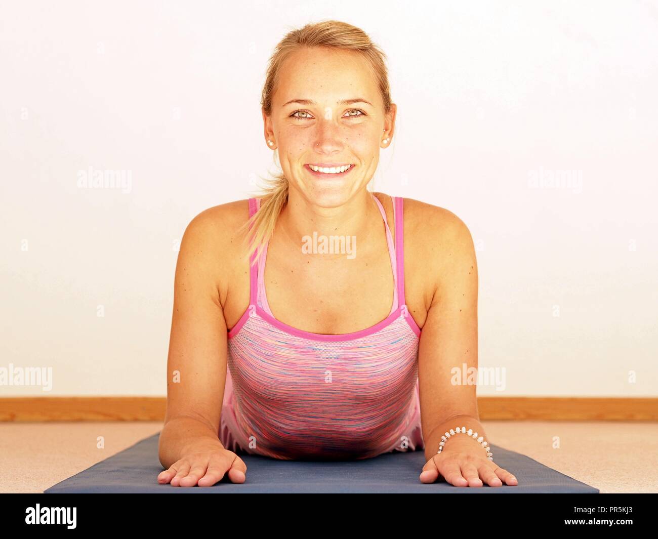 Beautiful young woman doing yoga asanas in pinke sports outfit. Stock Photo