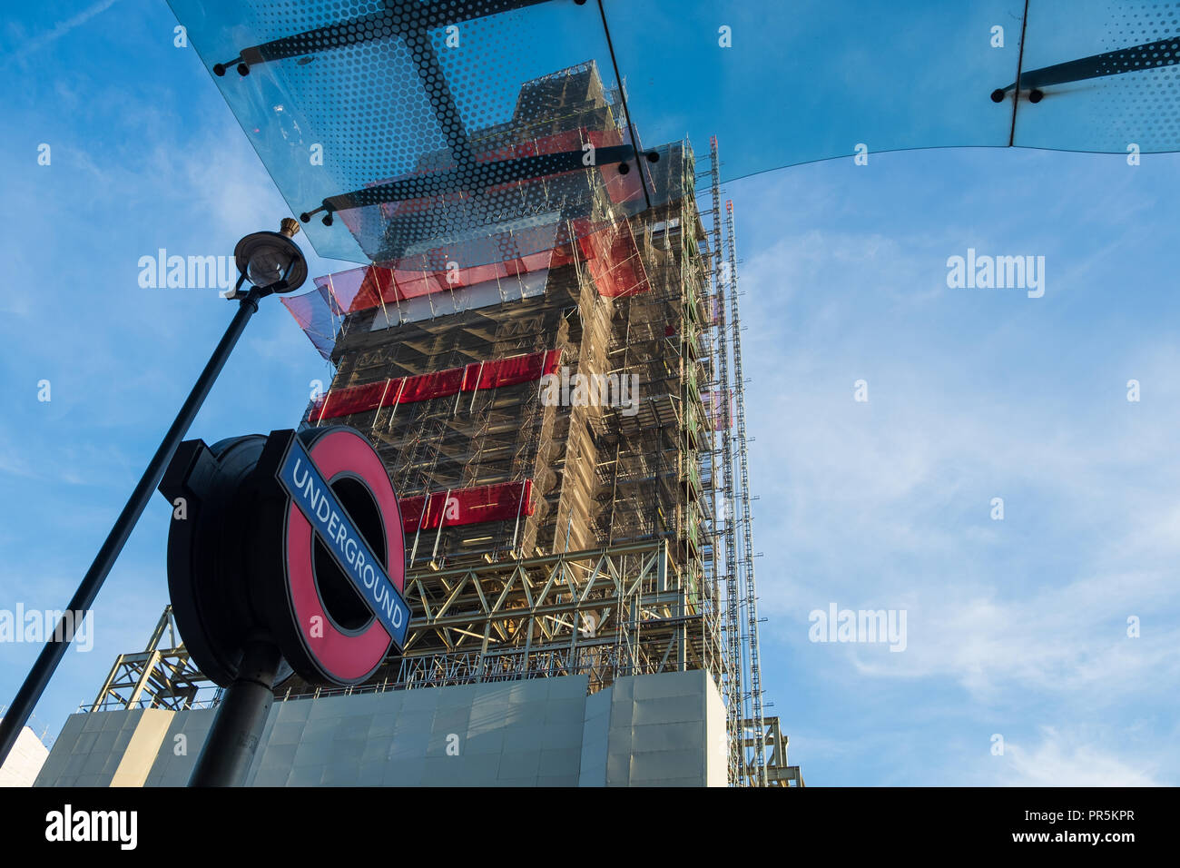 London, England - August 4, 2018: A bus stop of a London Underground (Tube) sign and the Big Ben under maintenance. These constitute some of London's  Stock Photo