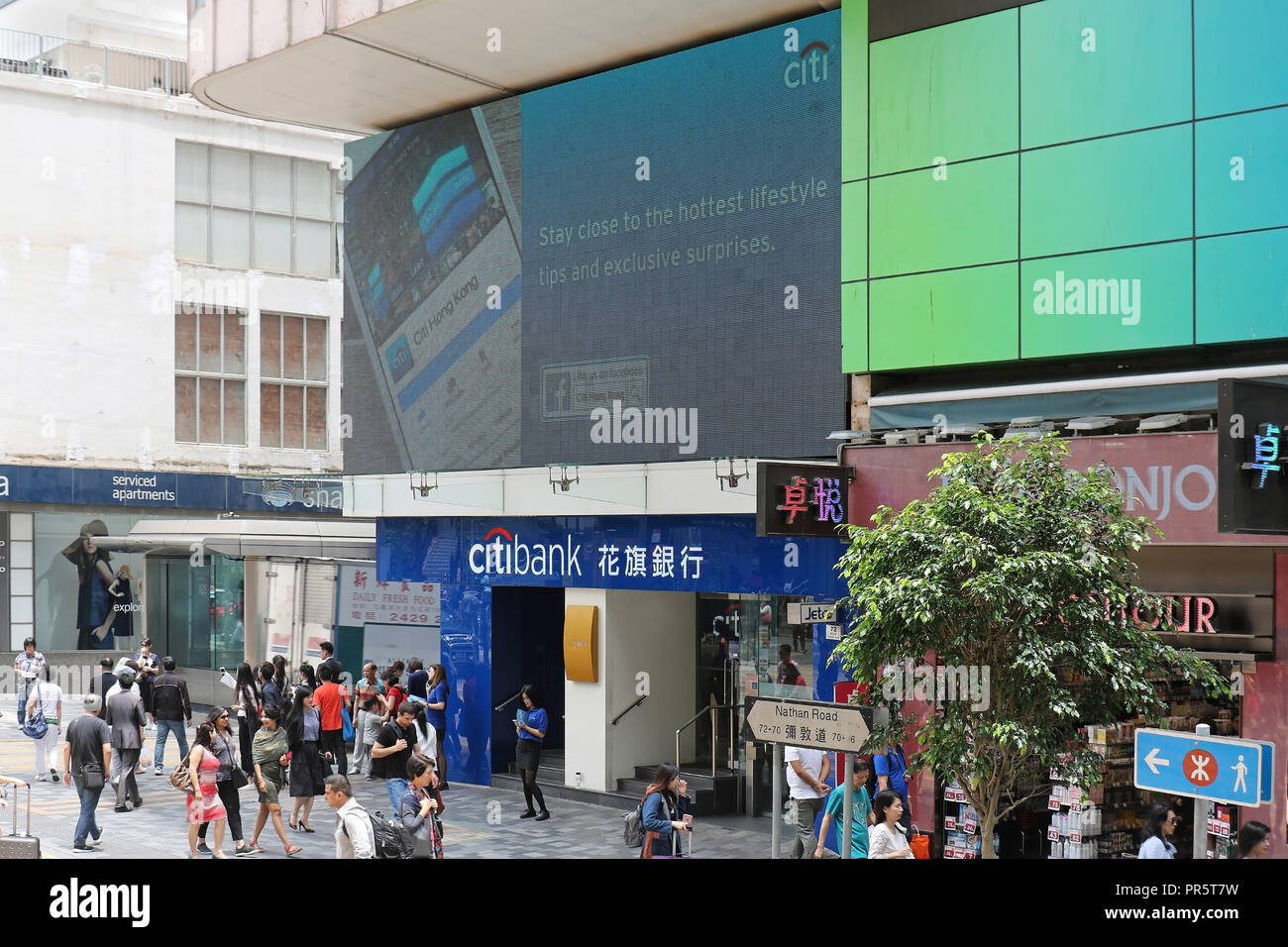 People in front of famous Citibank branch on Nathan Road in Kowloon part of Hong Kong with large advertisement display above the entrance Stock Photo