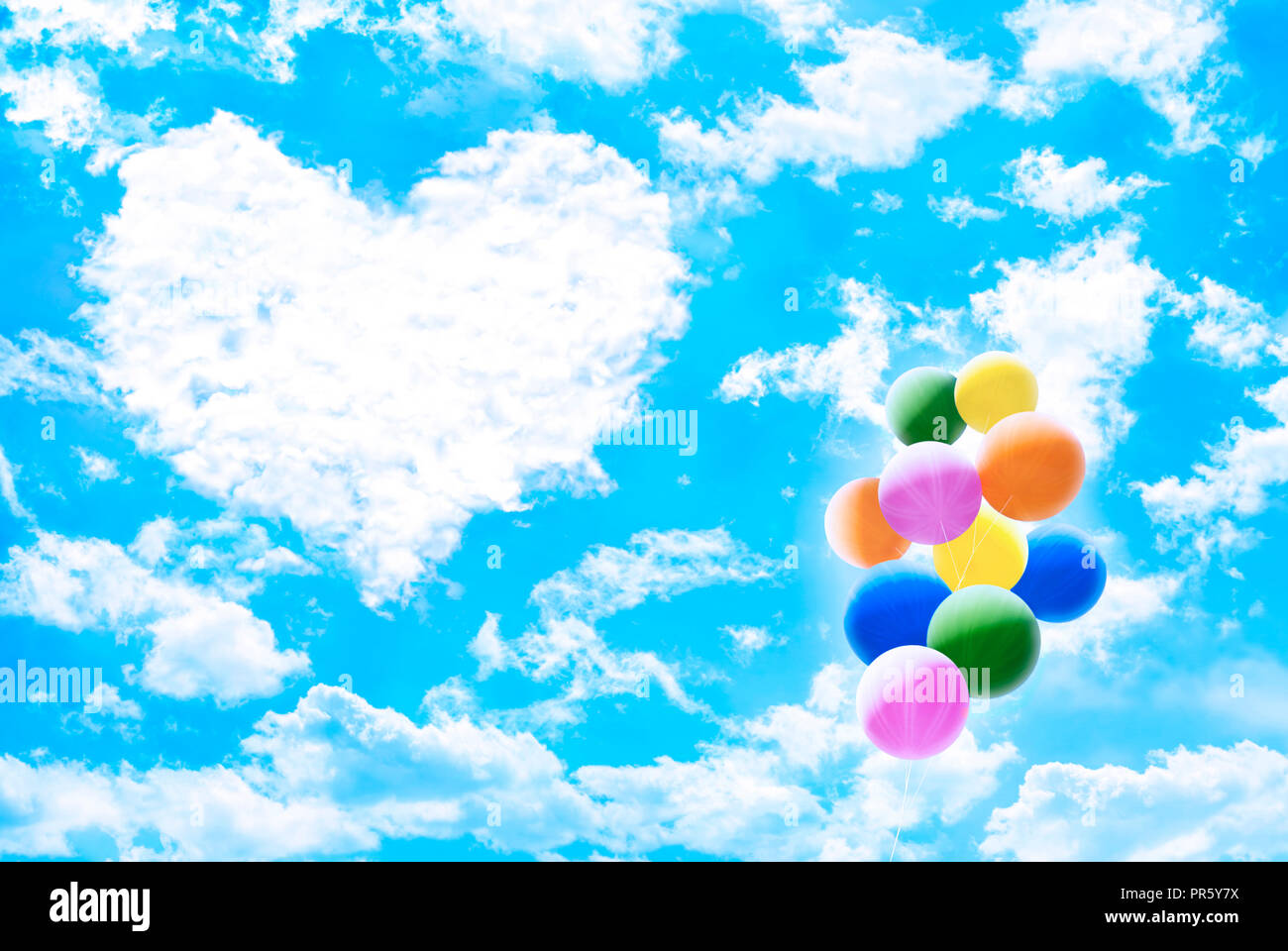 White clouds over blue sky forming “heart” shape with bunch of colorful ...
