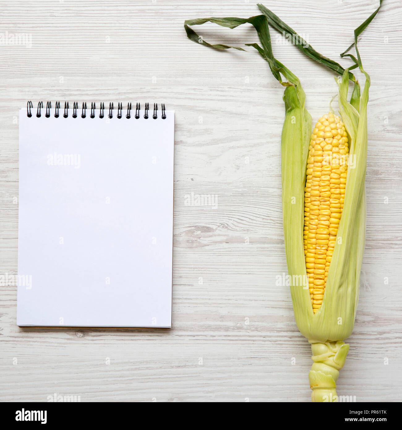 Corn Notepad Ear of corn and blank notepad on a white wooden background, top view ...