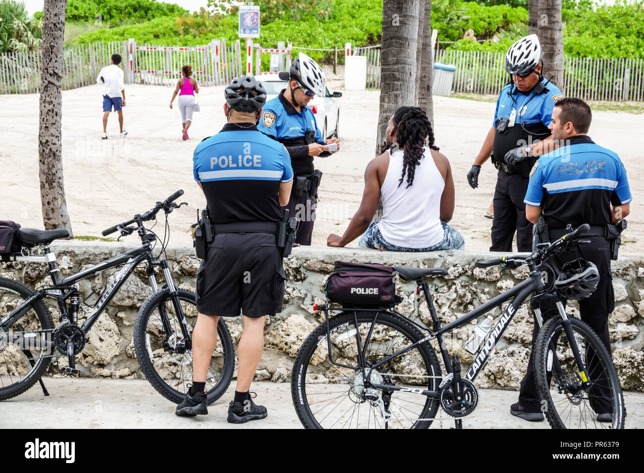 Miami Beach Florida,bicycle bicycles bicycling riding biking rider riders bike bikes,police,officer officers,questioning,Black man men male,FL18052720 Stock Photo