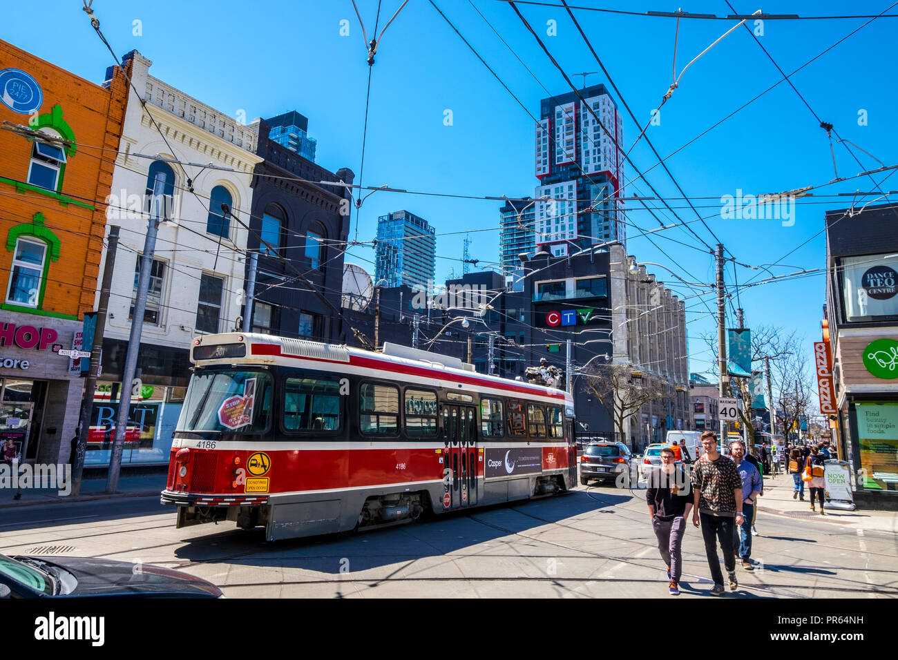 The bustle of downtown Toronto with pedestrians walking the sidewalk while a tram passes by Stock Photo