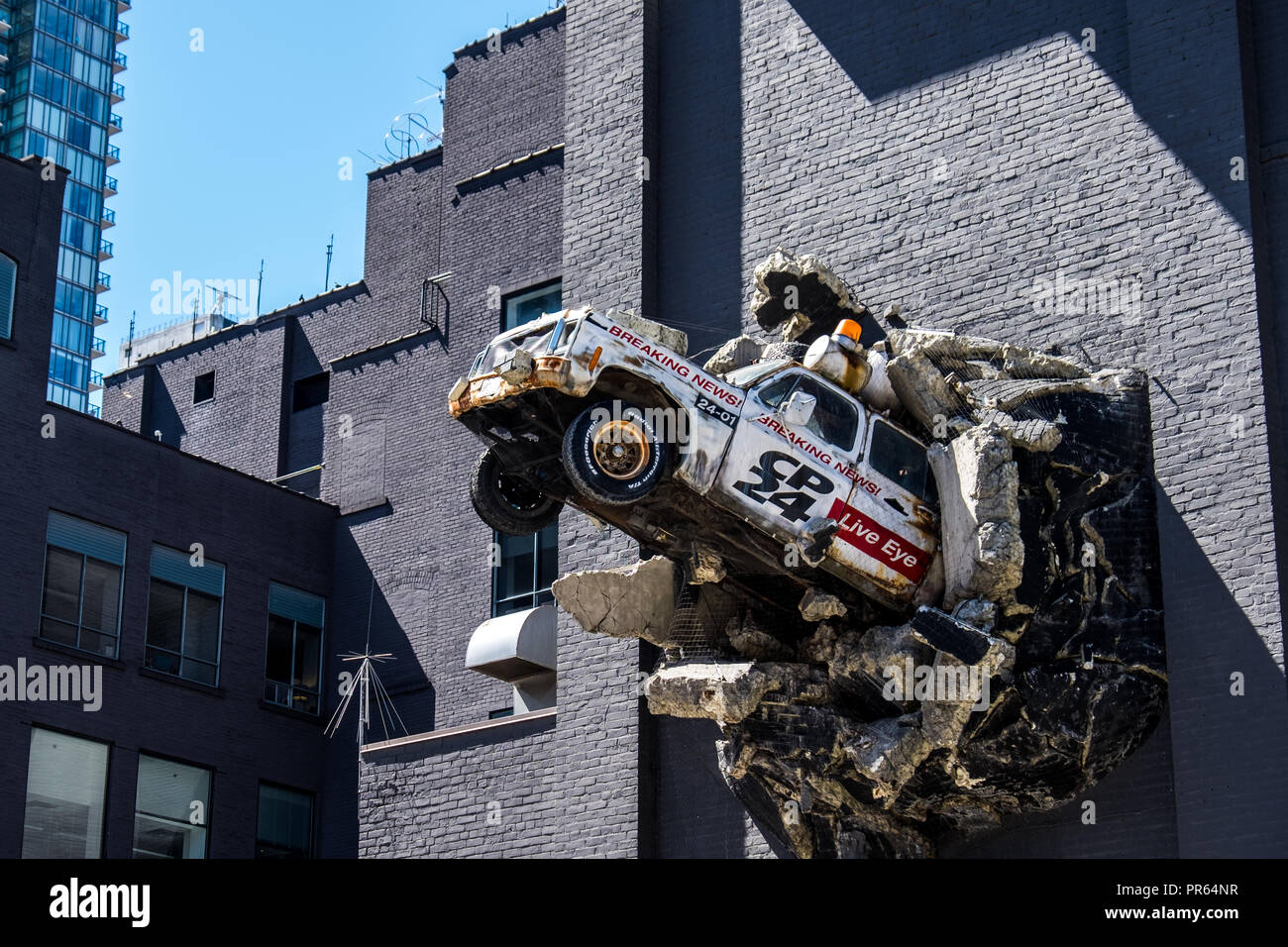 A piece of street art depicting a broadcast news vehicle bursting out of the wall of the Bell Media HQ in downtown Toronto Stock Photo