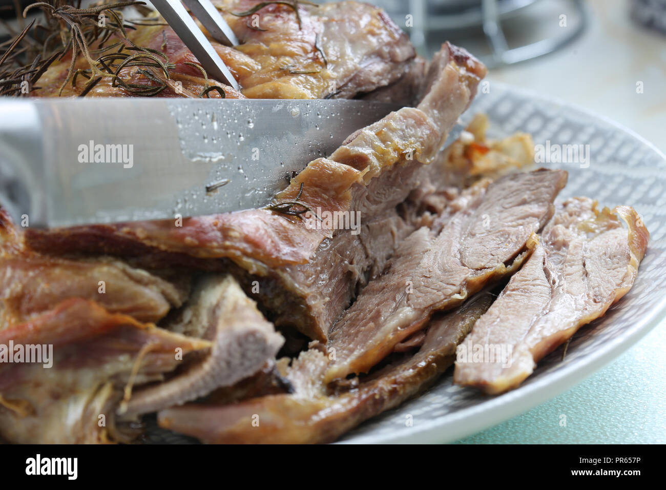 Roast Lamb Shoulder With A Rosemary Herb Garnish Being Carved With A ...