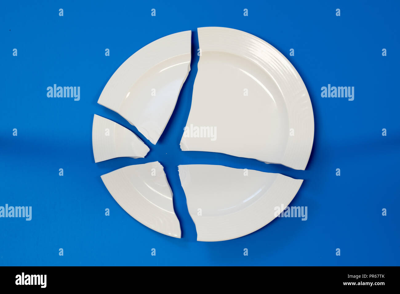 broken porcelain plate on a blue background Stock Photo Alamy