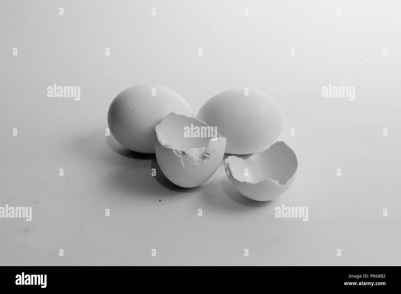 Three white eggs on a white isolated background, one egg broken in half, healthy food certificate, breakfast. Stock Photo