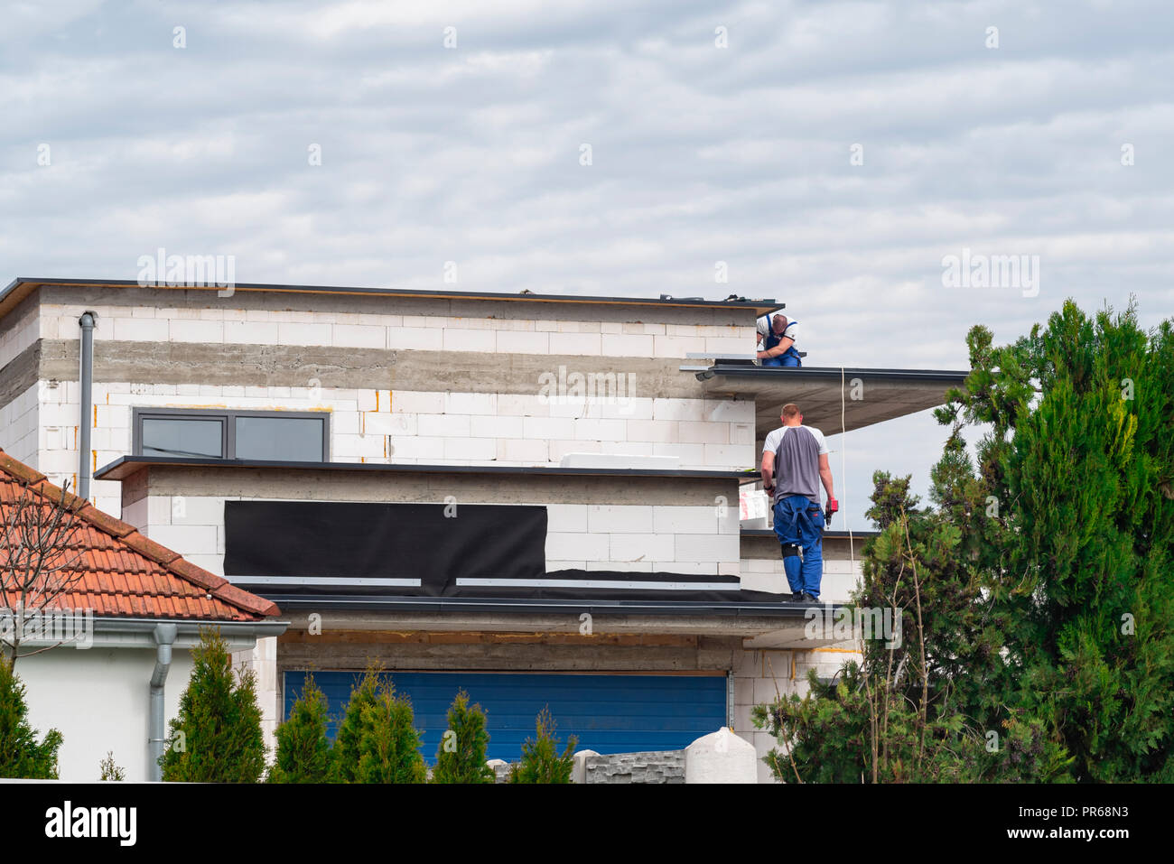 Builders build a house. Workers make a roof on top of the house in work