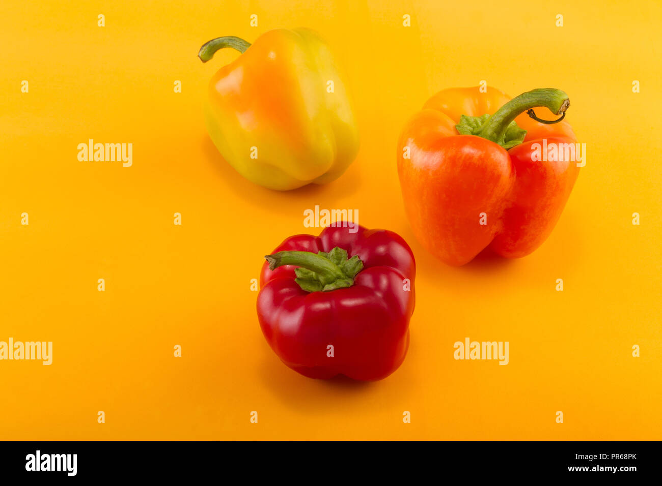 Sweet Bellpepper Two Orange Yellow And One Red Sweet Bellpeppers On A Yellow Background Three Pieces Studio Light Top View Stock Photo Alamy