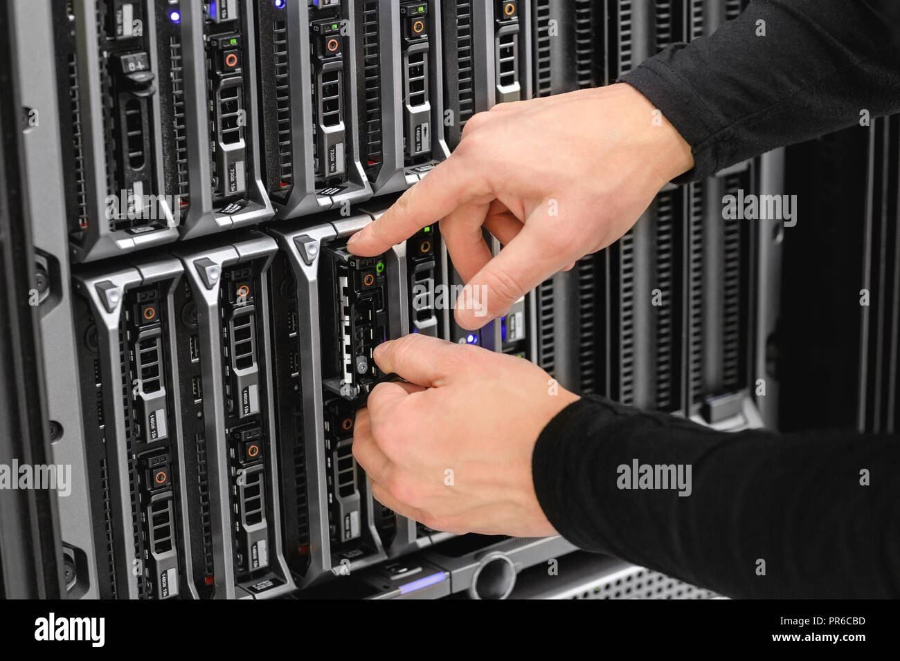 Male Technical Consultant Installing Blade Server In SAN At Data Stock Photo