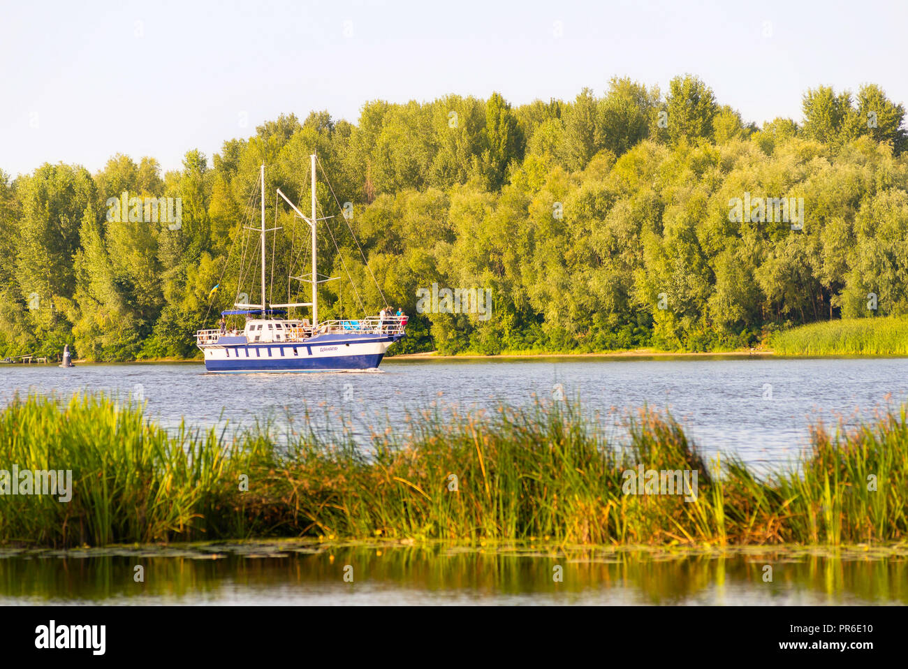Kiev / Ukraine - August 31, 2018 - The 'Danapr' boat navigates close to the shore covered by trees, on the Dnieper river in Kiev, Ukraine, during a cl Stock Photo