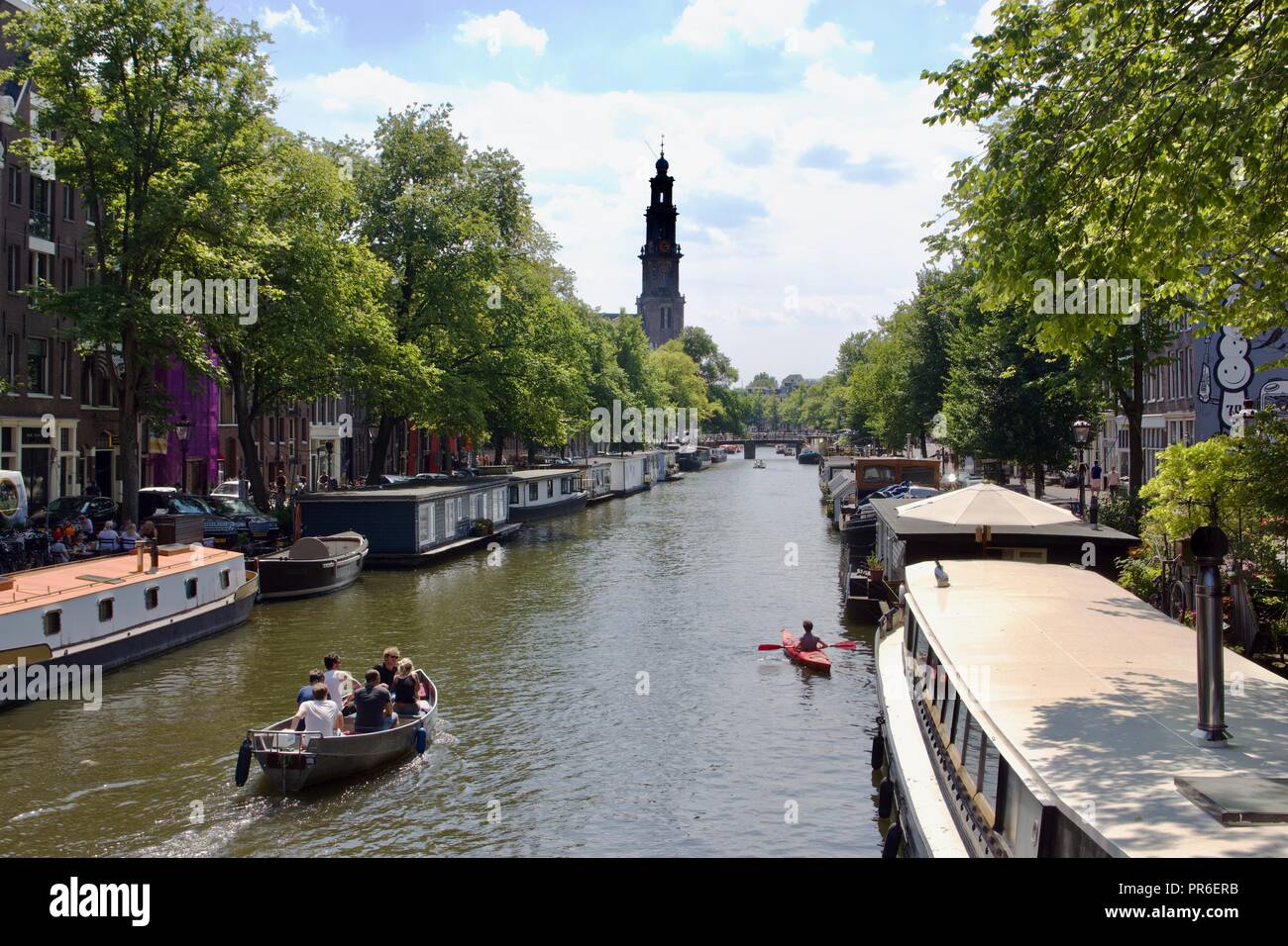 Three different types of boats: Motor boat, canal house boat and kayak on an Amsterdam canal on a summer day Stock Photo