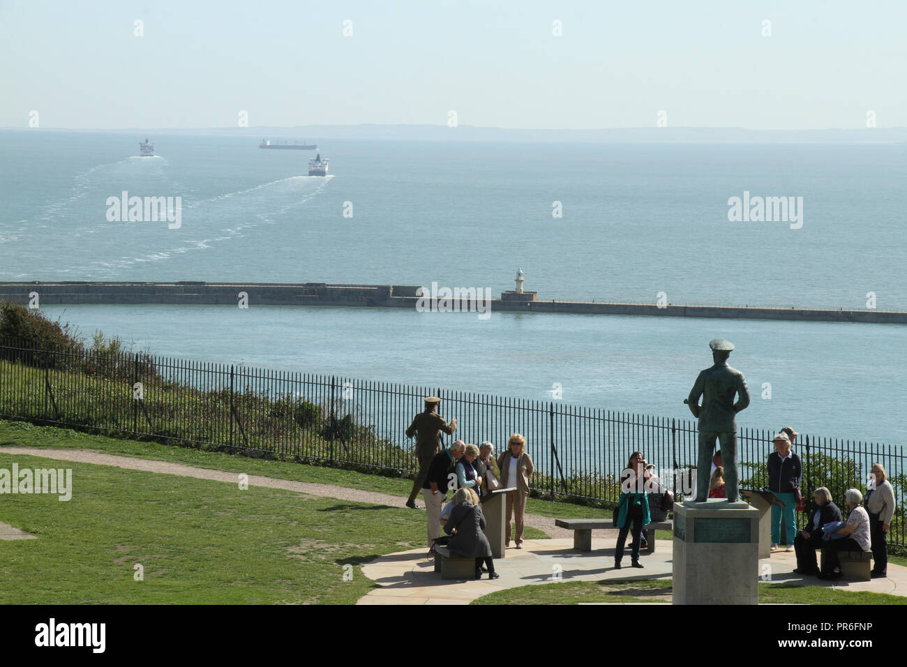 Dover, Kent, UK - September  30 2018:  Tourist stand by a statue of Admiral Sir Bertram Home Ramsay overlooking the Dover port wirh ferries sailing towards Calaris. General view of the coastal town of Dover and the  medieval Dover Castle overlooks the town from the iconic White Cliffs.. Credit: David Mbiyu Stock Photo