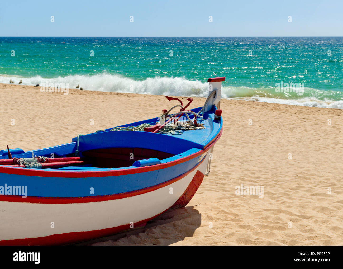 fishing boat painted in traditional colours, on Armacao de Pera beach Stock Photo