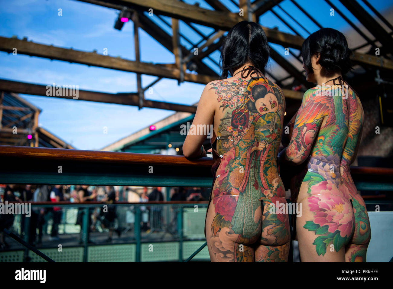 Two women show off their tattoos during the International tattoo convention at Tobacco Dock in east London. Stock Photo