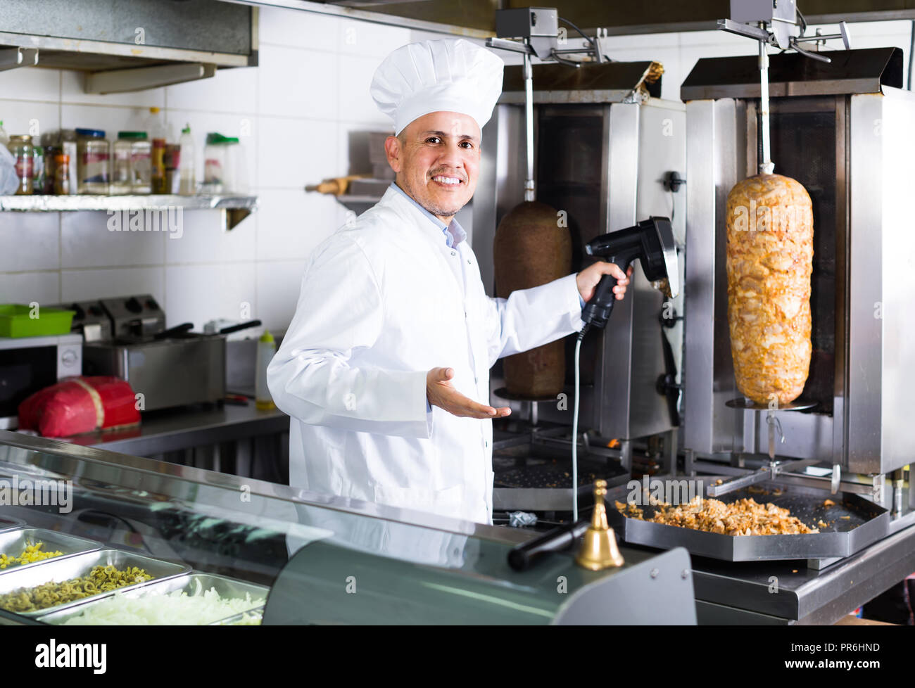 Happy Spanish Mature Man Chef Wearing Uniform Cutting Meat For