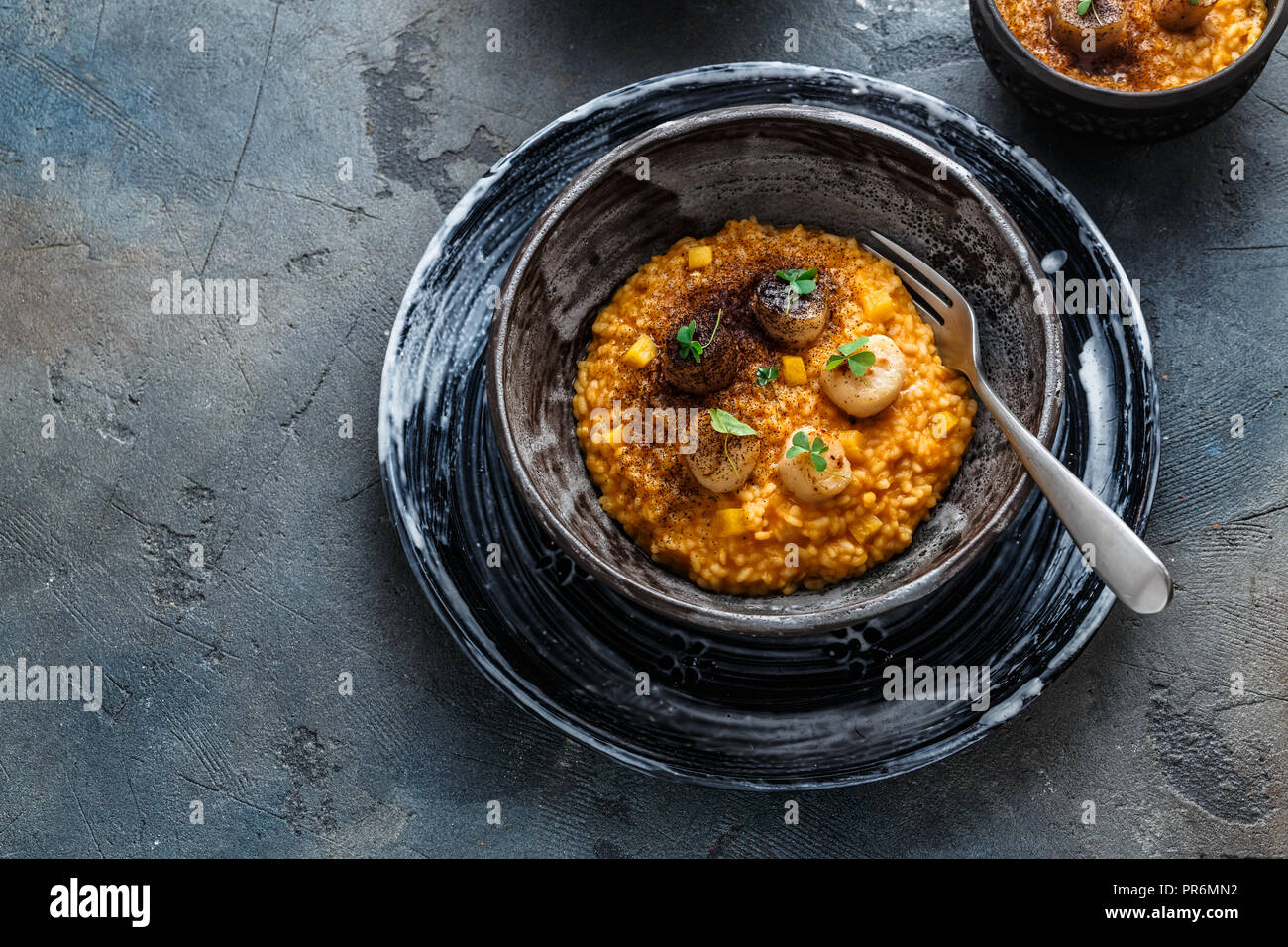Risotto with pumpkin and scallops, on stone background, copy space