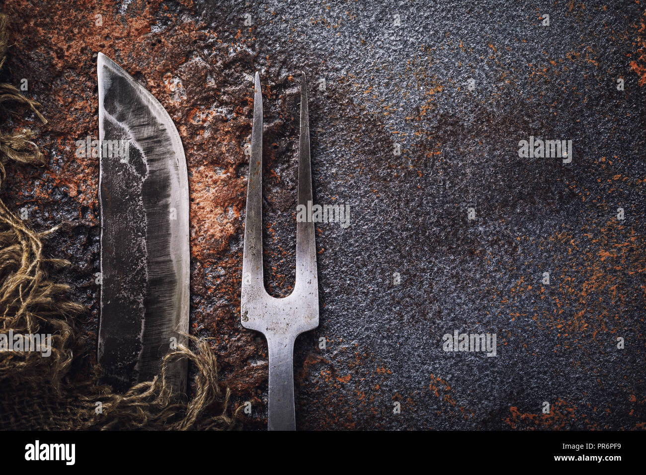 Knife and fork for meat on rusty table. Top view of vintage kitchen